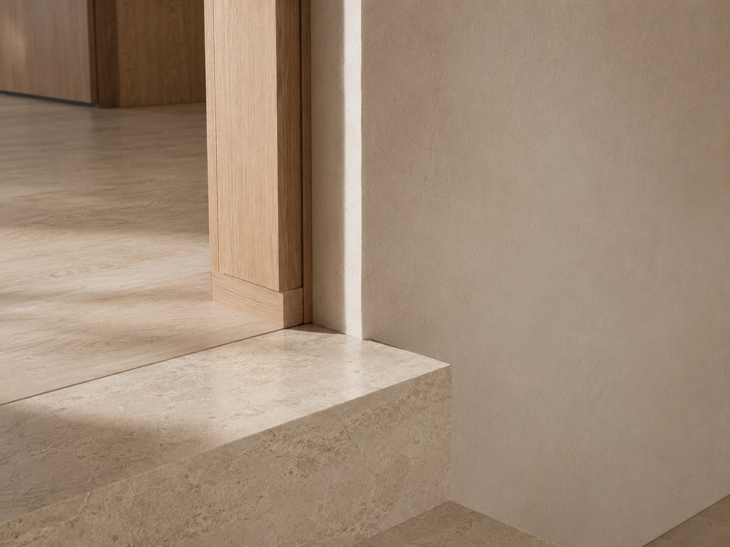 Close architectural detail where a limestone step meets a pale oak threshold, timber floor, and warm plaster wall.